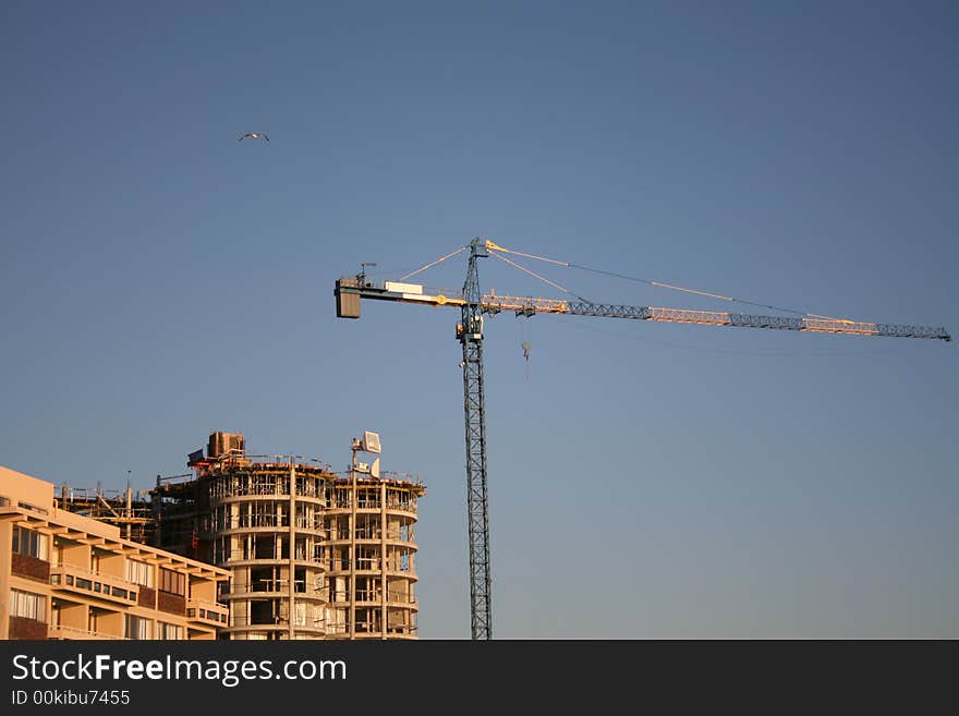 High Crane against a blue sky close to a building site