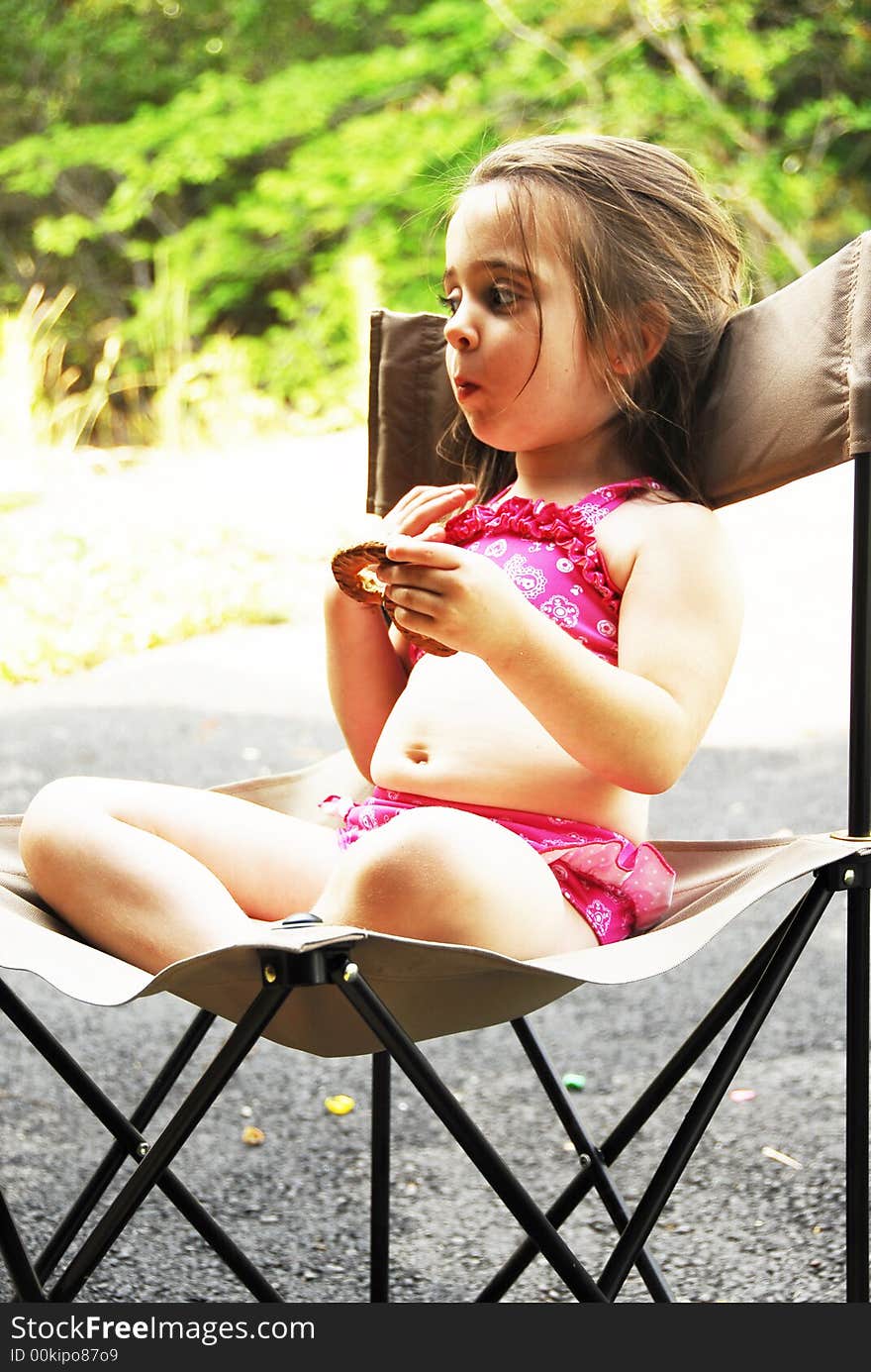 Cute little girl eating a big pretzel in an outdoor setting. Cute little girl eating a big pretzel in an outdoor setting.