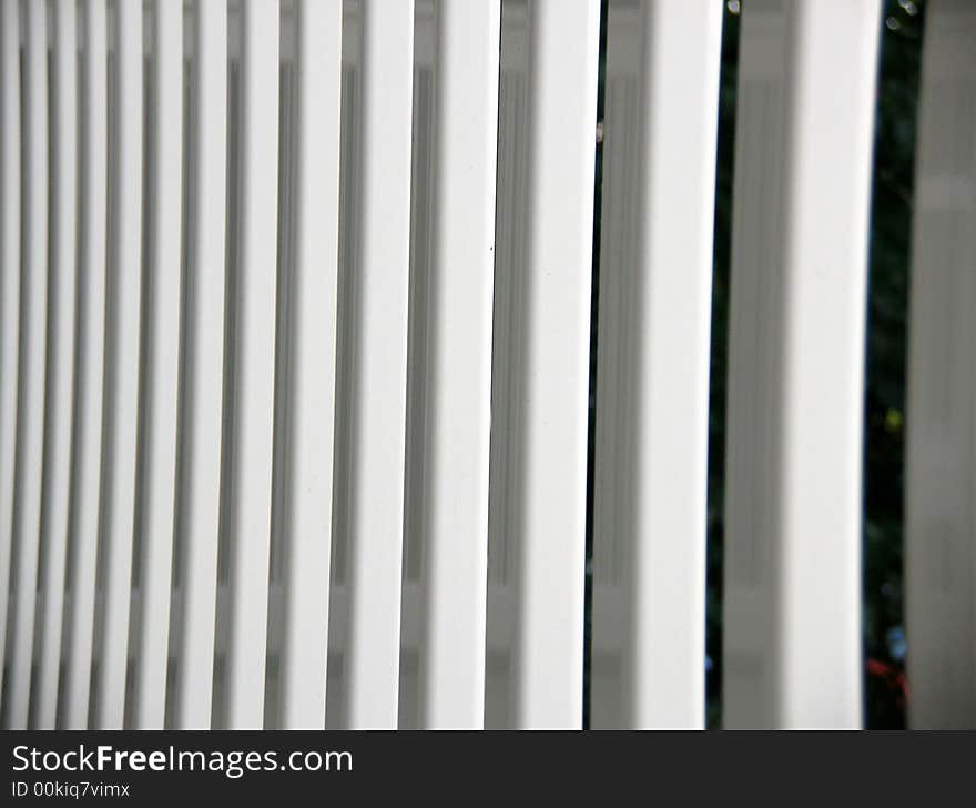 The vertical spindles on our white porch fence photographed in the early evening.