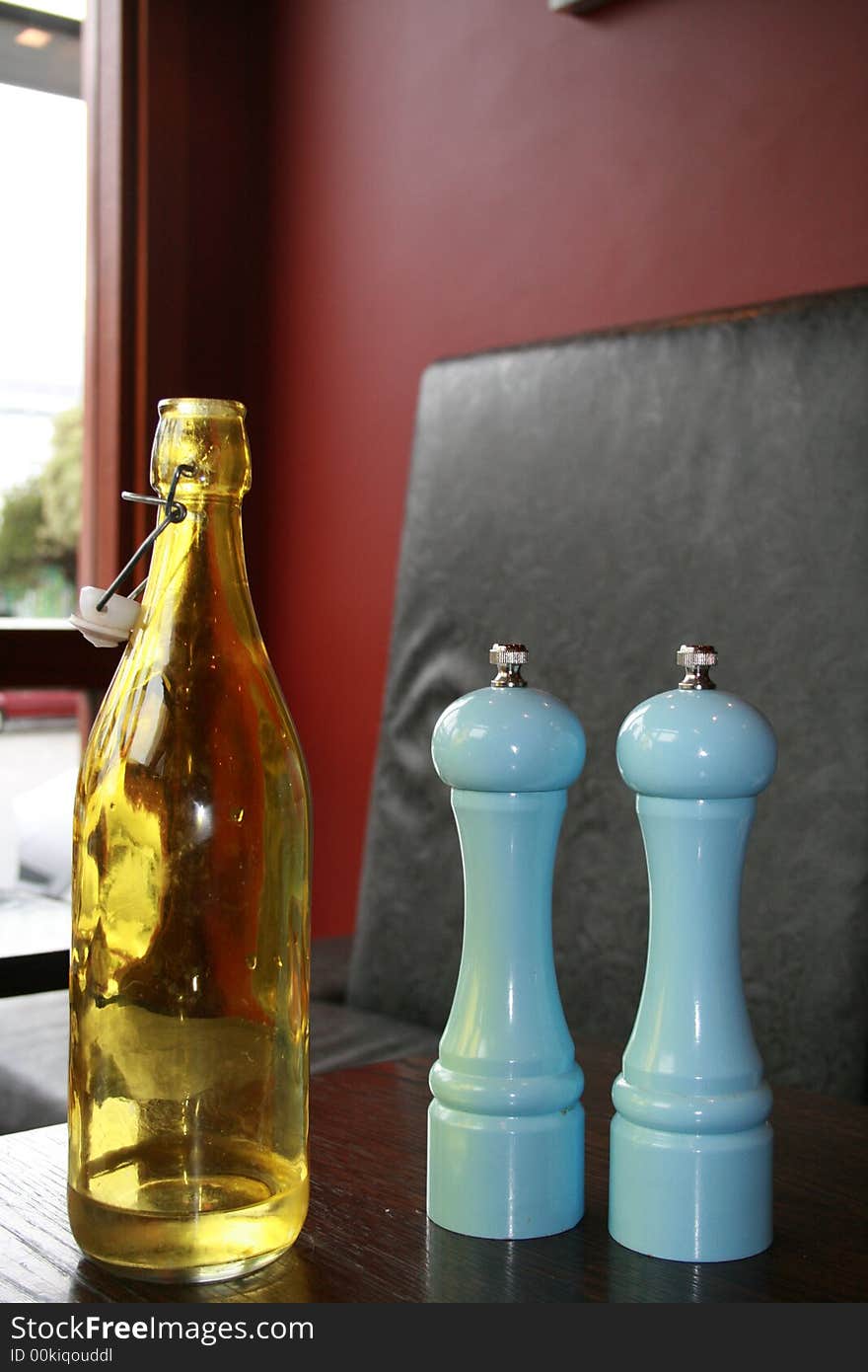 Yellow water bottle with baby blue salt and pepper grinders in a cafe/restaurant setting. Yellow water bottle with baby blue salt and pepper grinders in a cafe/restaurant setting