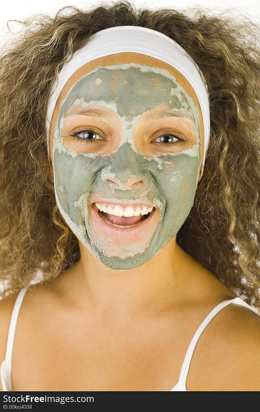 Young happy woman with green purifying mask. She's looking at camera. Young happy woman with green purifying mask. She's looking at camera.