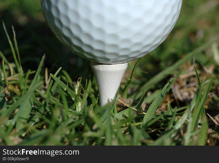 A white golf ball on a tee.  A macro image. A white golf ball on a tee.  A macro image.