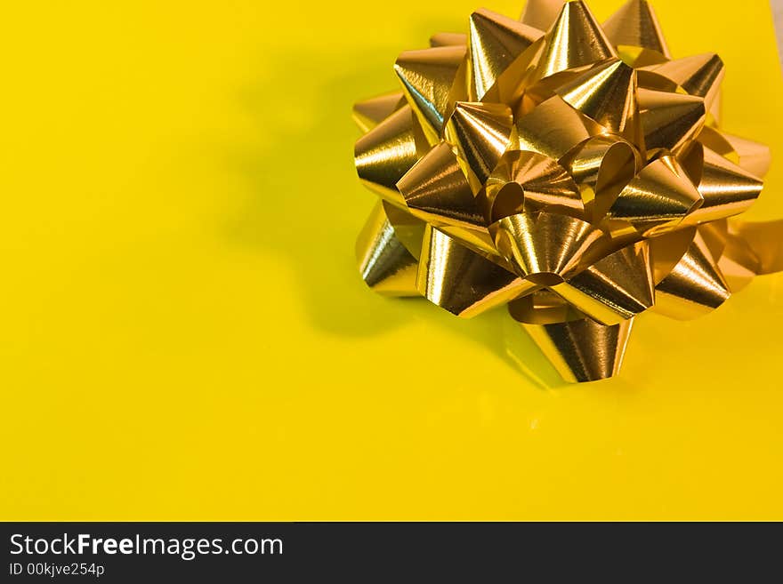 Shiny golden bow on a bright yellow background. Shiny golden bow on a bright yellow background