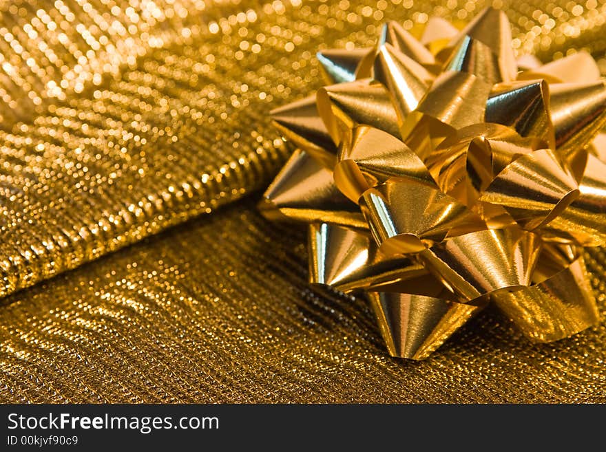 Shiny golden bow on a golden textured background. Shiny golden bow on a golden textured background