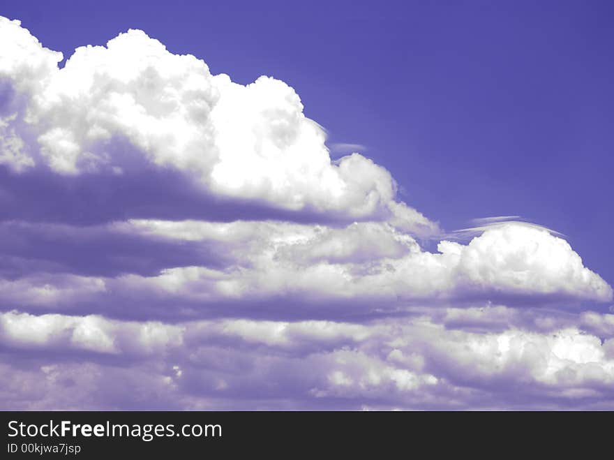 Puffy ominous clouds encroaching in on clear blue skies. Puffy ominous clouds encroaching in on clear blue skies