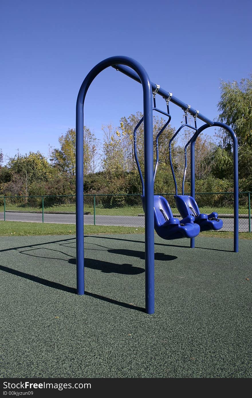 Two empty swings on a public playground.