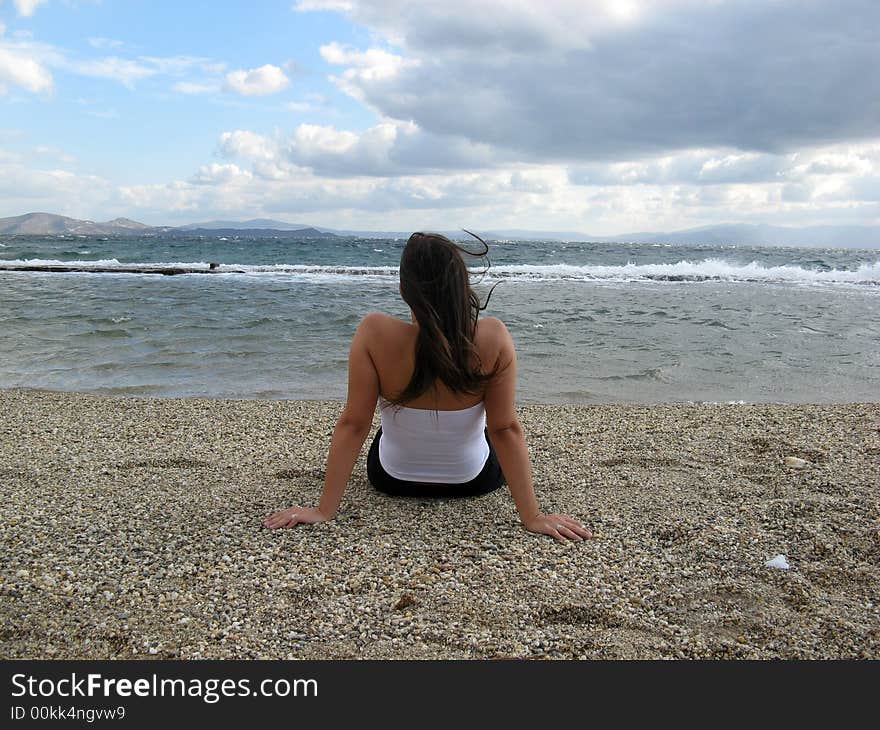 A young woman in the beach in daylight seating on sand. A young woman in the beach in daylight seating on sand