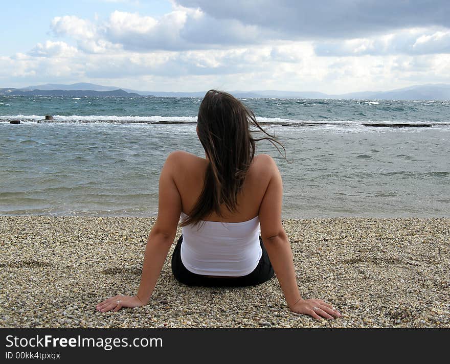 A young woman in the beach in daylight seating on sand. A young woman in the beach in daylight seating on sand