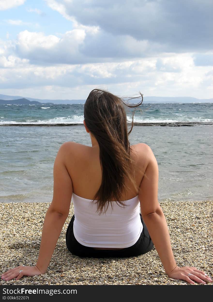 A young woman in the beach in daylight seating on sand. A young woman in the beach in daylight seating on sand