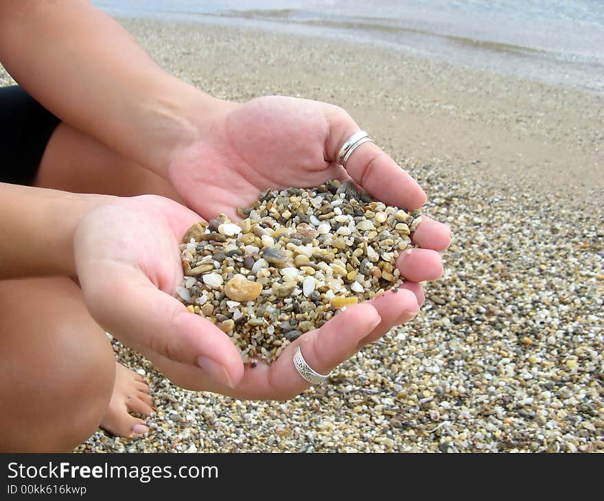 Female hands full of pebbles in the beach. Female hands full of pebbles in the beach