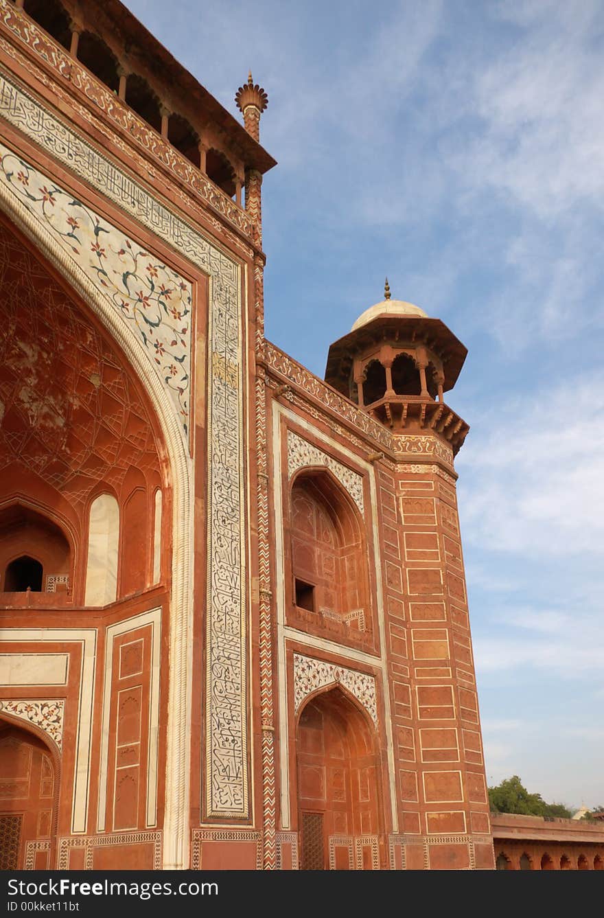 Fragment of red-brick decorated minaret in taj mahal mausoleum site with blue sky. Agra, India. Fragment of red-brick decorated minaret in taj mahal mausoleum site with blue sky. Agra, India