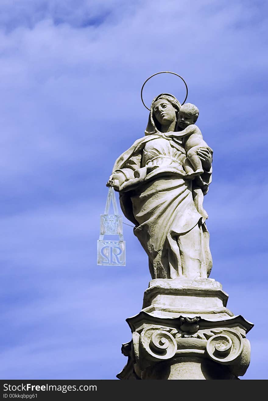 A statue of Our Lady with Child Jesus atop a lonely pillar in a square of the city of Bologna, Italy, as a symbol of protection of the people