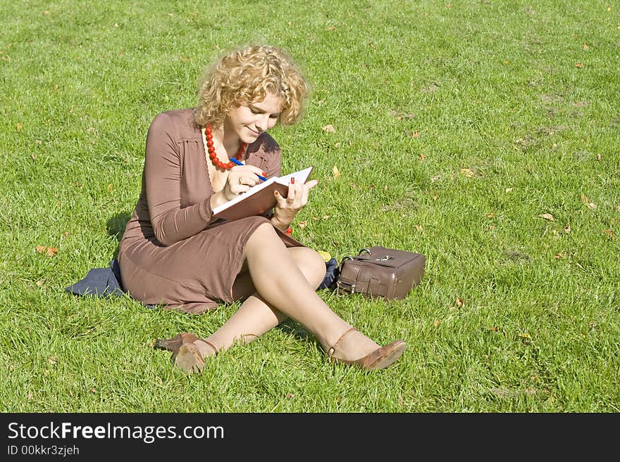 Business women with notebook sits on grass