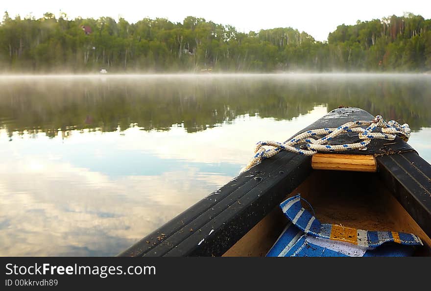 The bow of a canoe with the view of a peaceful lake in the background. The bow of a canoe with the view of a peaceful lake in the background.