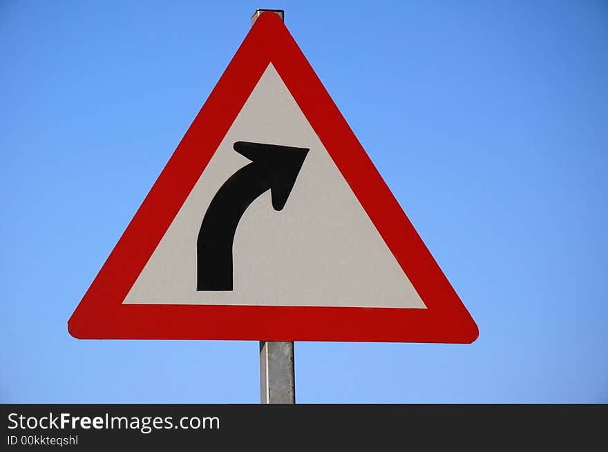 A road sign warning about a right turn ahead. A road sign warning about a right turn ahead.