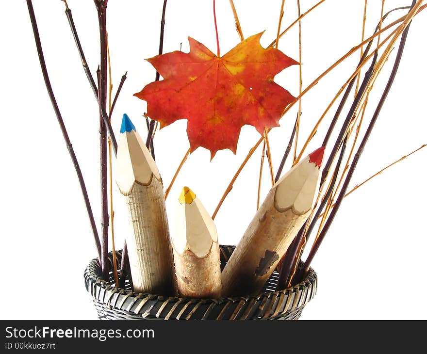 Autumn composition with leaf: coloured pencils in basket on white background