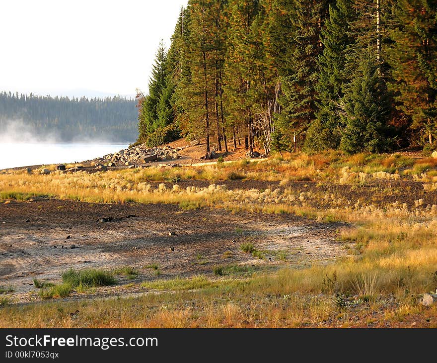 Morning light at Crescent Lake, Oregon. We see the fog lifting from the water of the lake, autumn colors are just beginning to show in the trees and plants around the lake. Morning light at Crescent Lake, Oregon. We see the fog lifting from the water of the lake, autumn colors are just beginning to show in the trees and plants around the lake