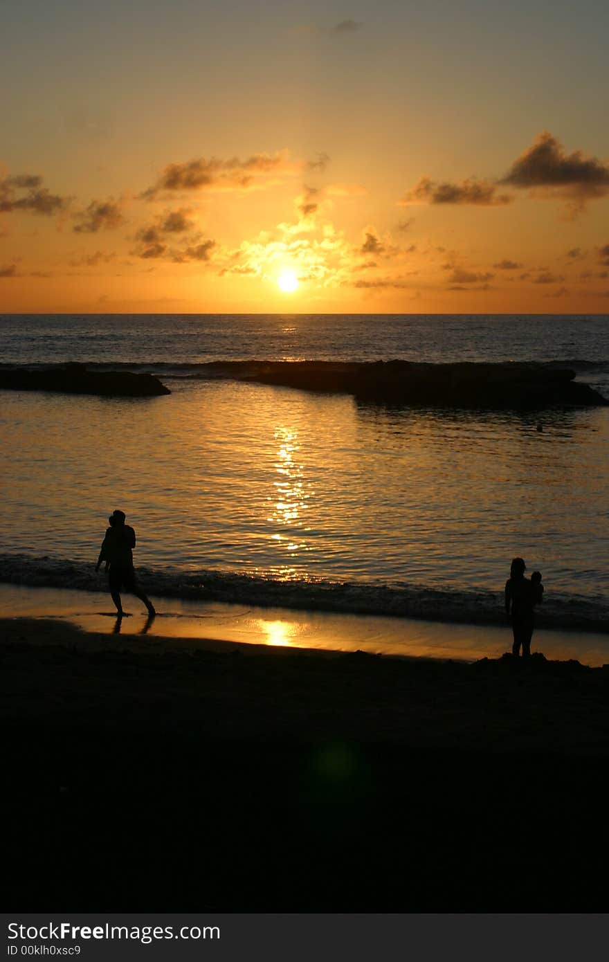 People silhouetted against a tropical hawaiian sunset. People silhouetted against a tropical hawaiian sunset.