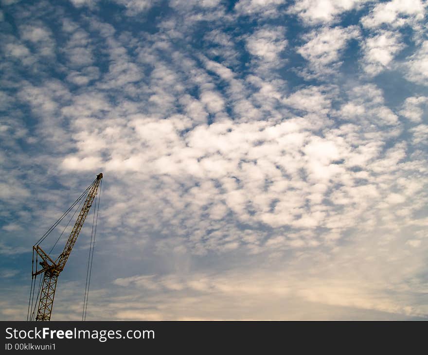 A tall crane silhouetted against a altocumulus mackerel sky. A tall crane silhouetted against a altocumulus mackerel sky.