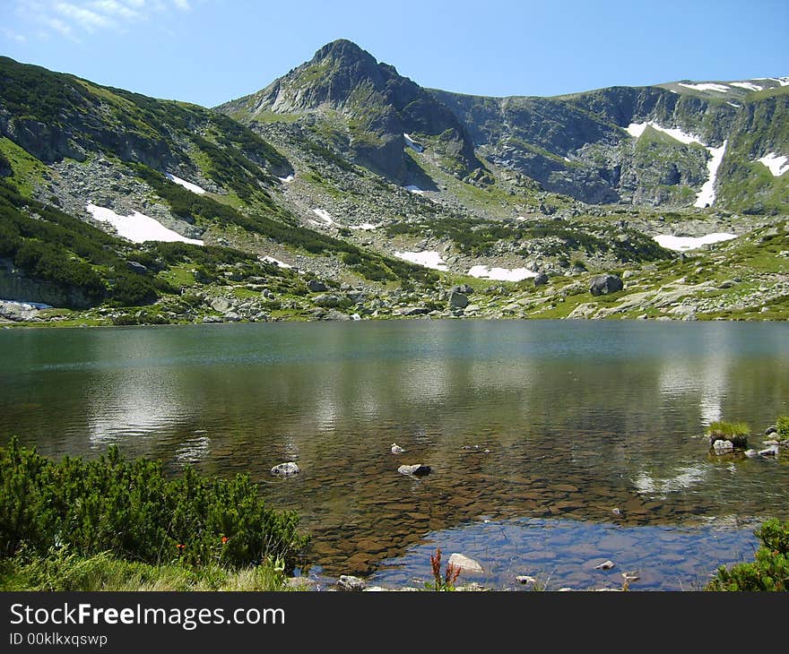 Green rock mountain reflected in clear lake. Green rock mountain reflected in clear lake