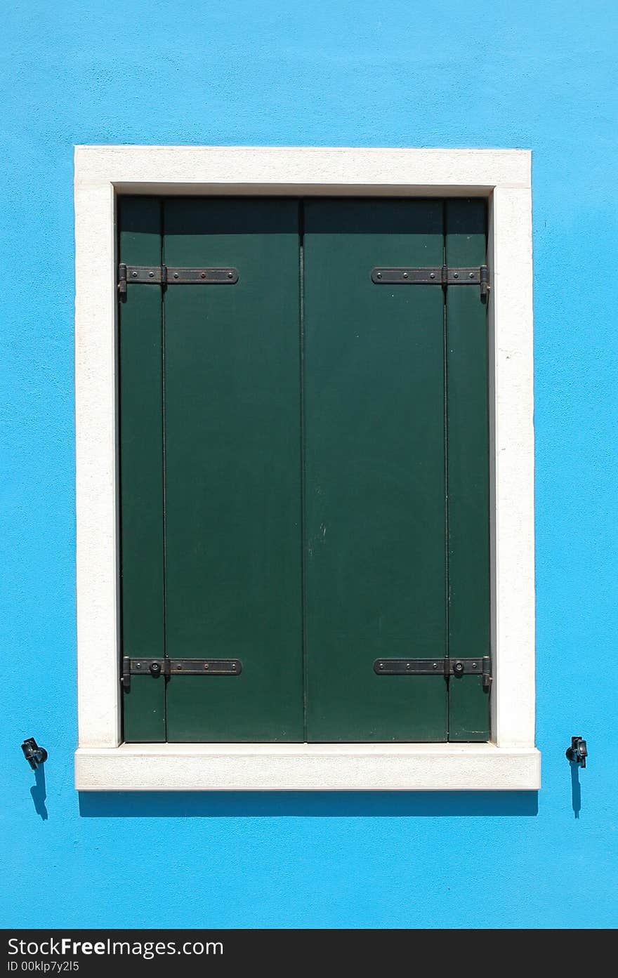 Closed window on a bright blue wall of a house ont he island of Burano, outside of Venice Italy. Closed window on a bright blue wall of a house ont he island of Burano, outside of Venice Italy.