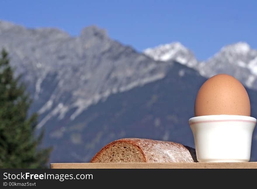 Close-up of egg and bread with alpine mountain range blurred in the background. Close-up of egg and bread with alpine mountain range blurred in the background