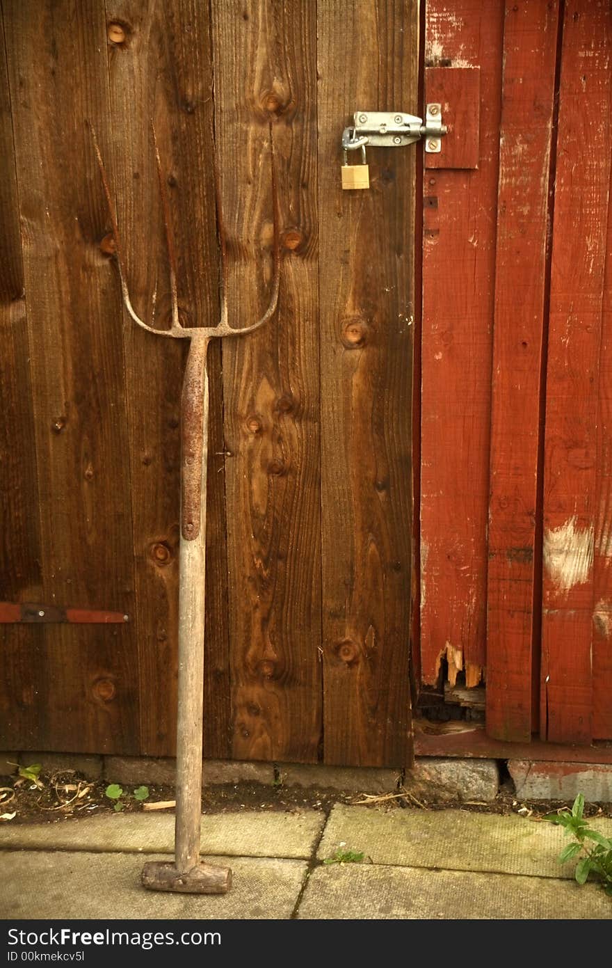 A pitchfork laying against an old wooden door.