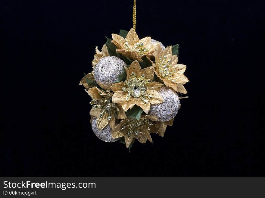 A gold and silver christmas decoration photographed against a black background