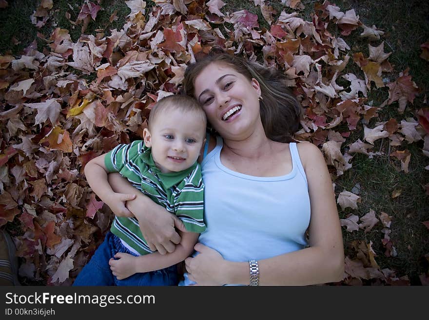 Son and Mother being affectionate on a pile of leaves. Son and Mother being affectionate on a pile of leaves