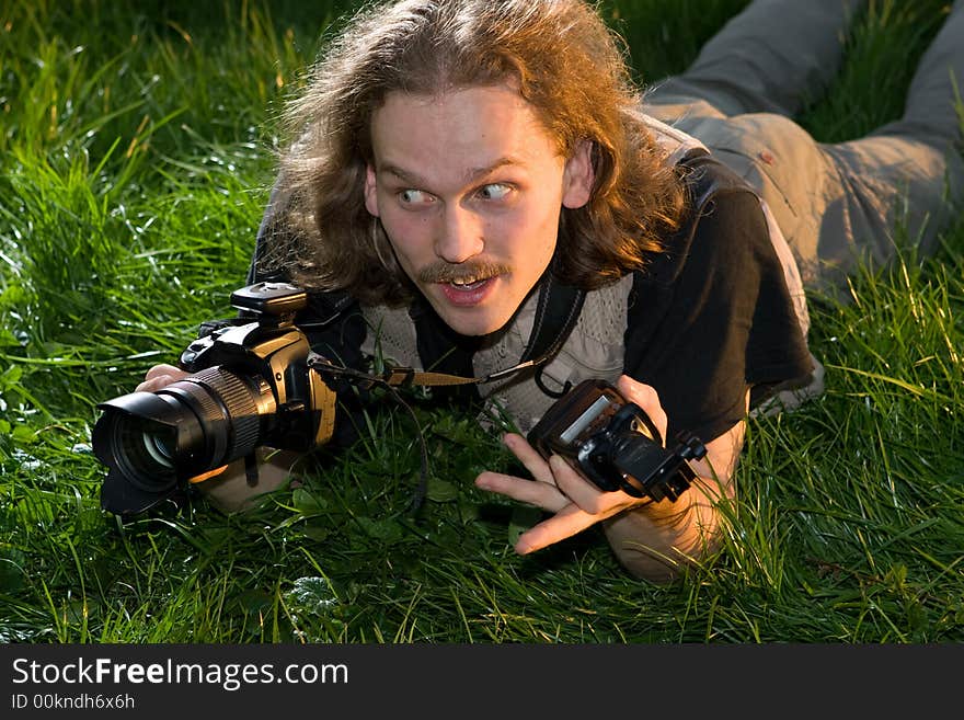 The photographer with the camera lays on a green grass