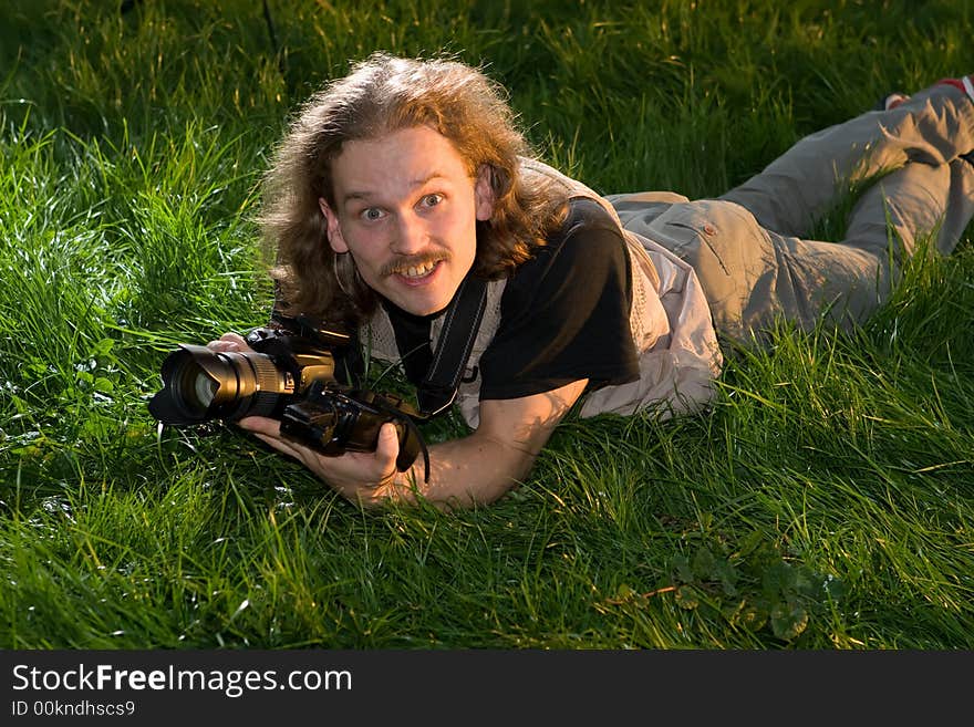 The photographer with the camera lays on a green grass