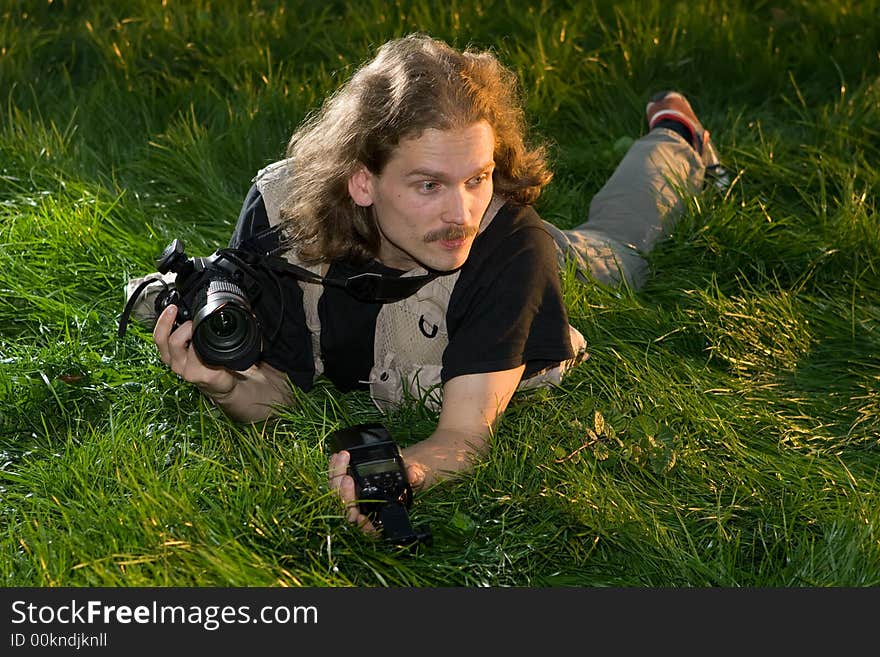 The photographer with the camera lays on a green grass