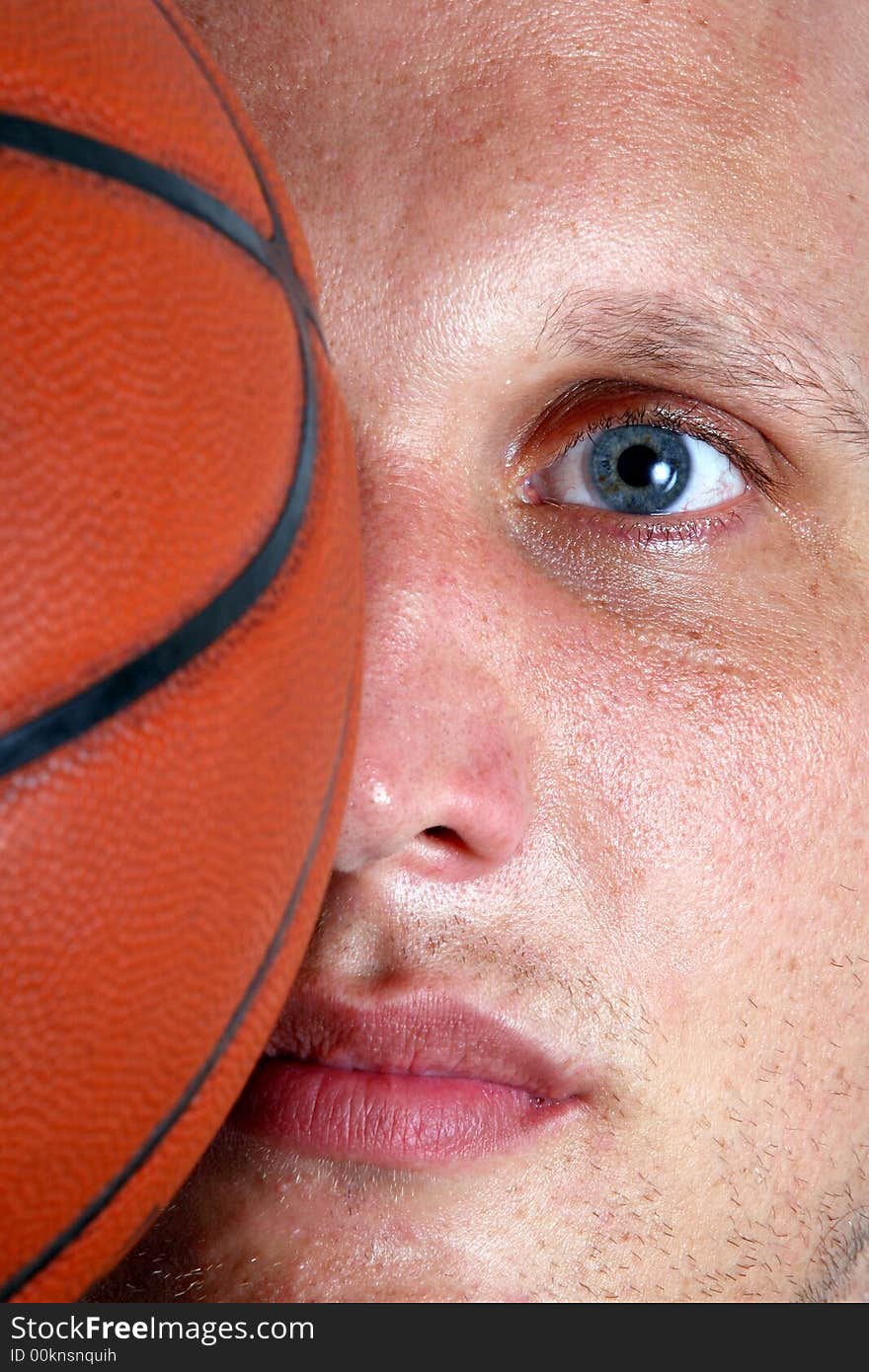 A closeup of a basketball player with half of his face covered with a ball!. A closeup of a basketball player with half of his face covered with a ball!