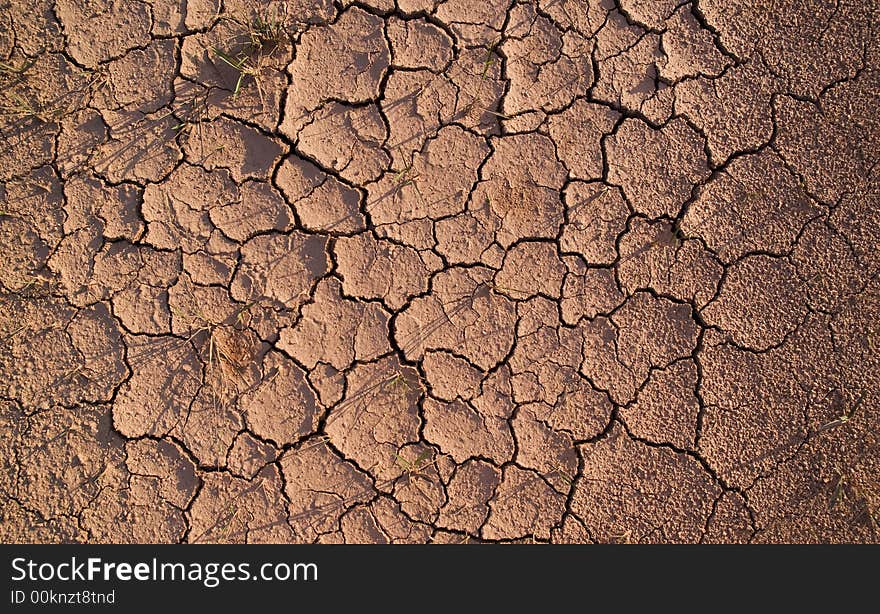 Dirt track with dry mud, cracked with gaps and holes