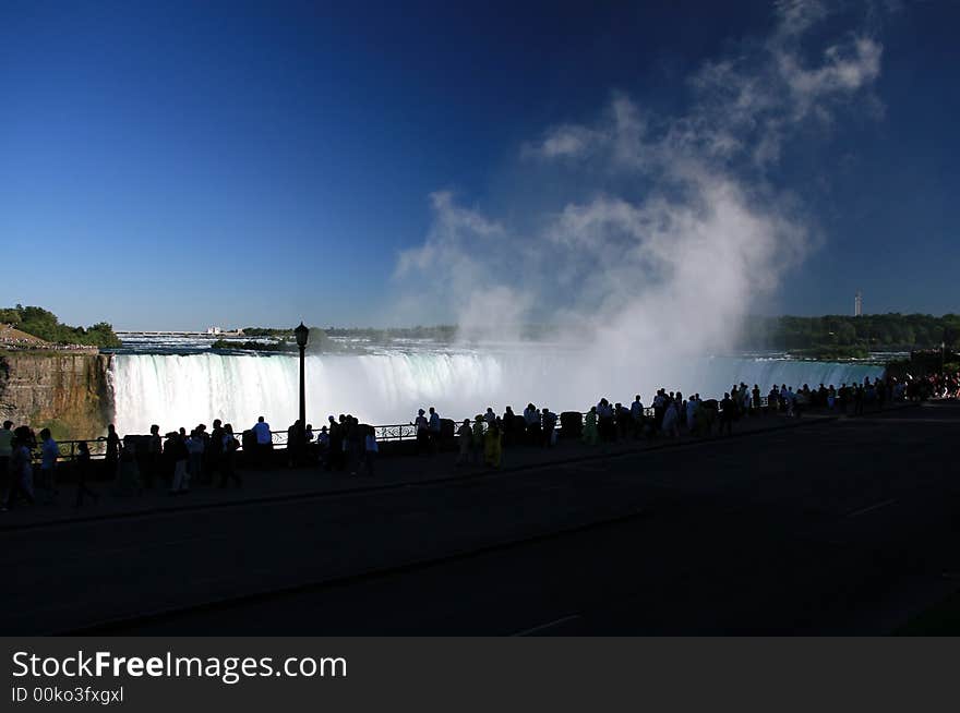 Silhouetted against the falls of Niagara these people watch the mists rise at the Horseshoe Falls. Silhouetted against the falls of Niagara these people watch the mists rise at the Horseshoe Falls.