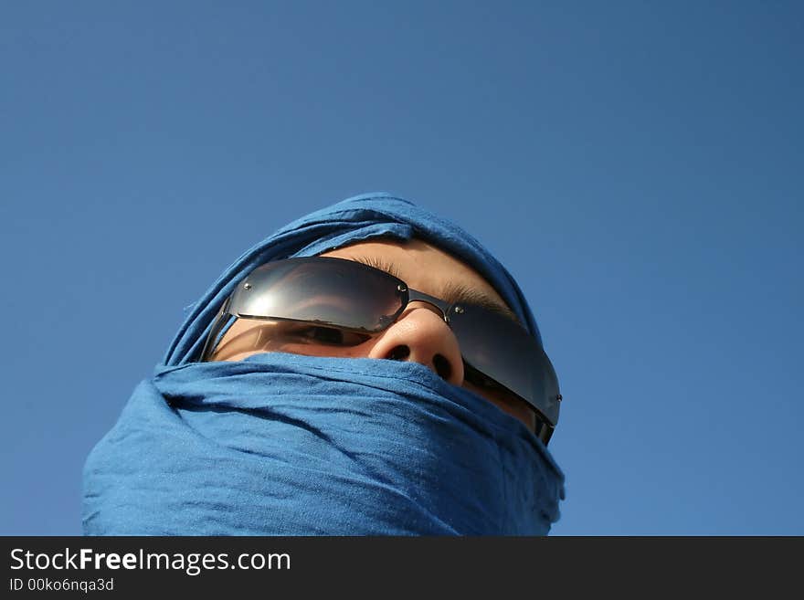 Face of a man in sahar desert covered with blue fabric