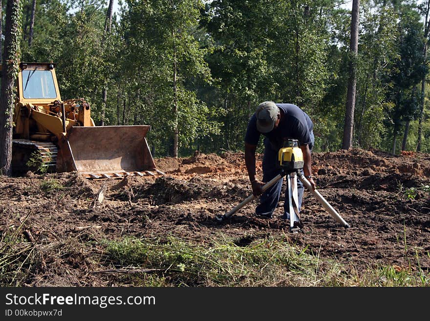 Construction worker setting transit level on home construction site. Construction worker setting transit level on home construction site