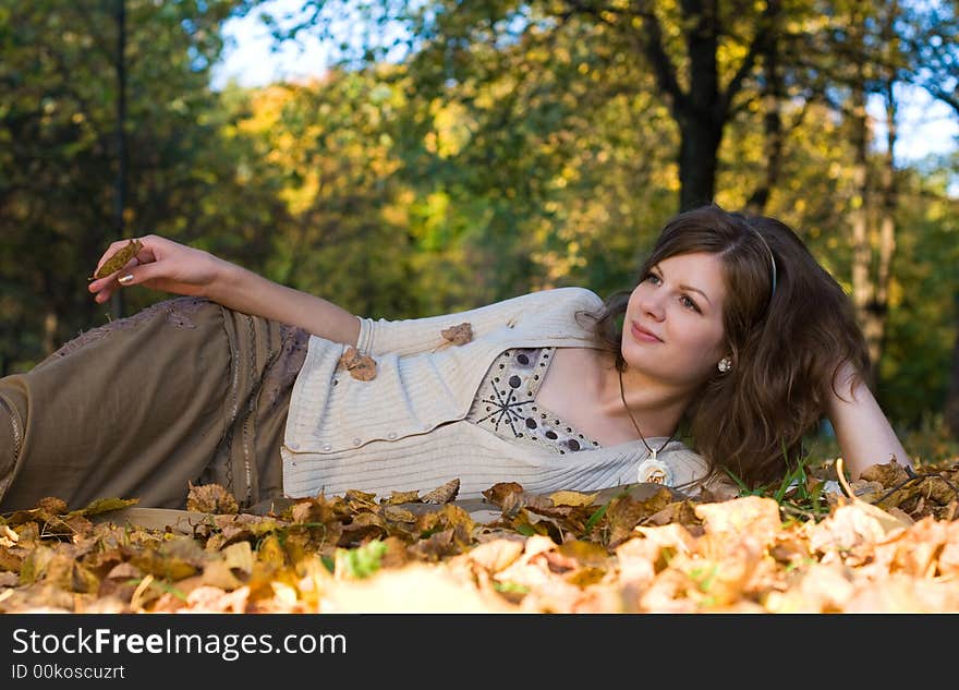 Girl lying on autumn leaves in park. Girl lying on autumn leaves in park