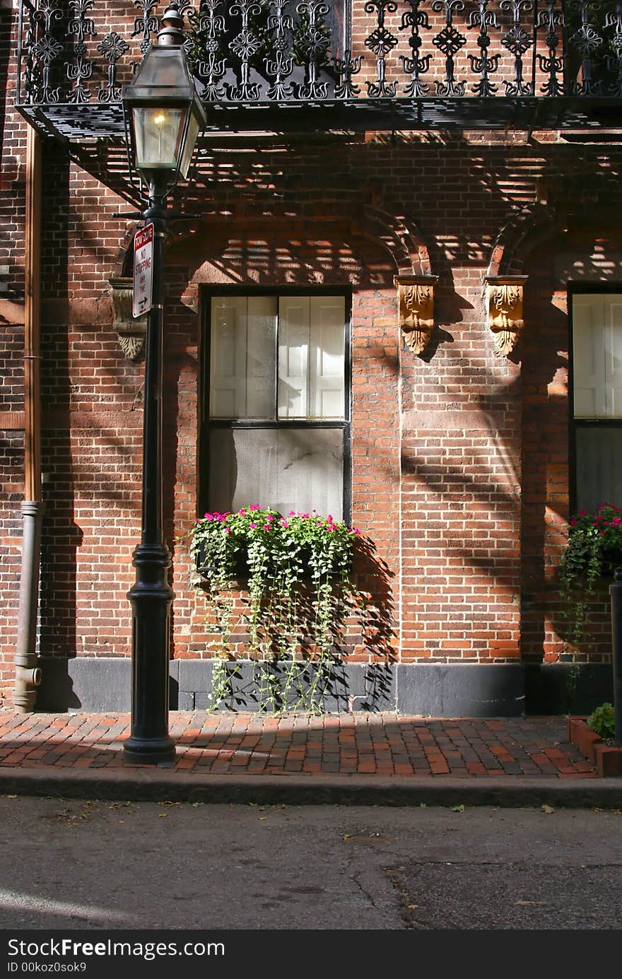 Side street in boston, showing window box flowers in bloom and detail of brick townhouses with iron fire escape and gas streetlamp. Side street in boston, showing window box flowers in bloom and detail of brick townhouses with iron fire escape and gas streetlamp