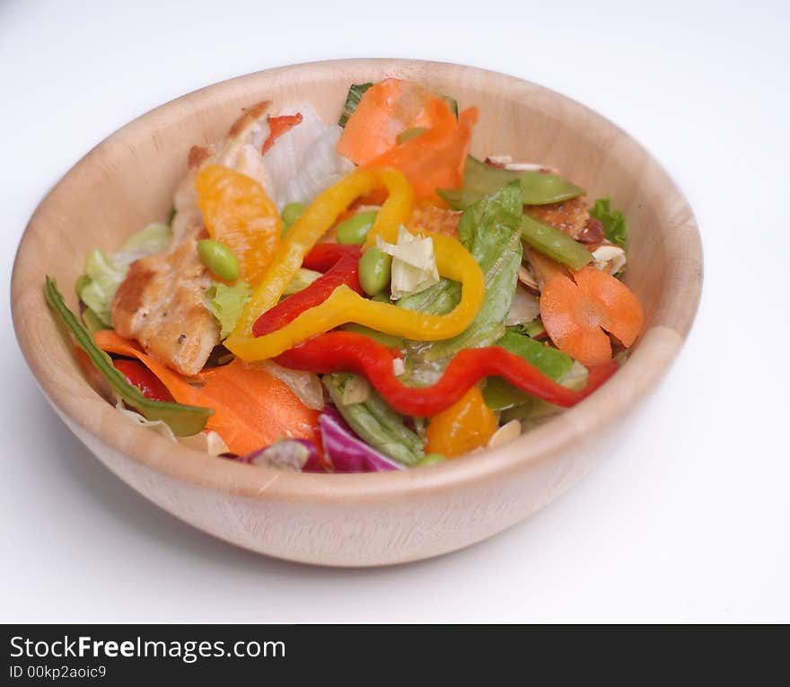 Delicious healthy salad with chicken as a protein in a wooden bowl.