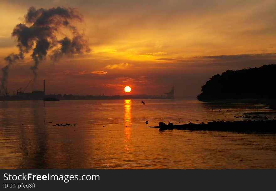 Sun just appearing over horizon in a landscape polluted by heavy industries. Sun just appearing over horizon in a landscape polluted by heavy industries.