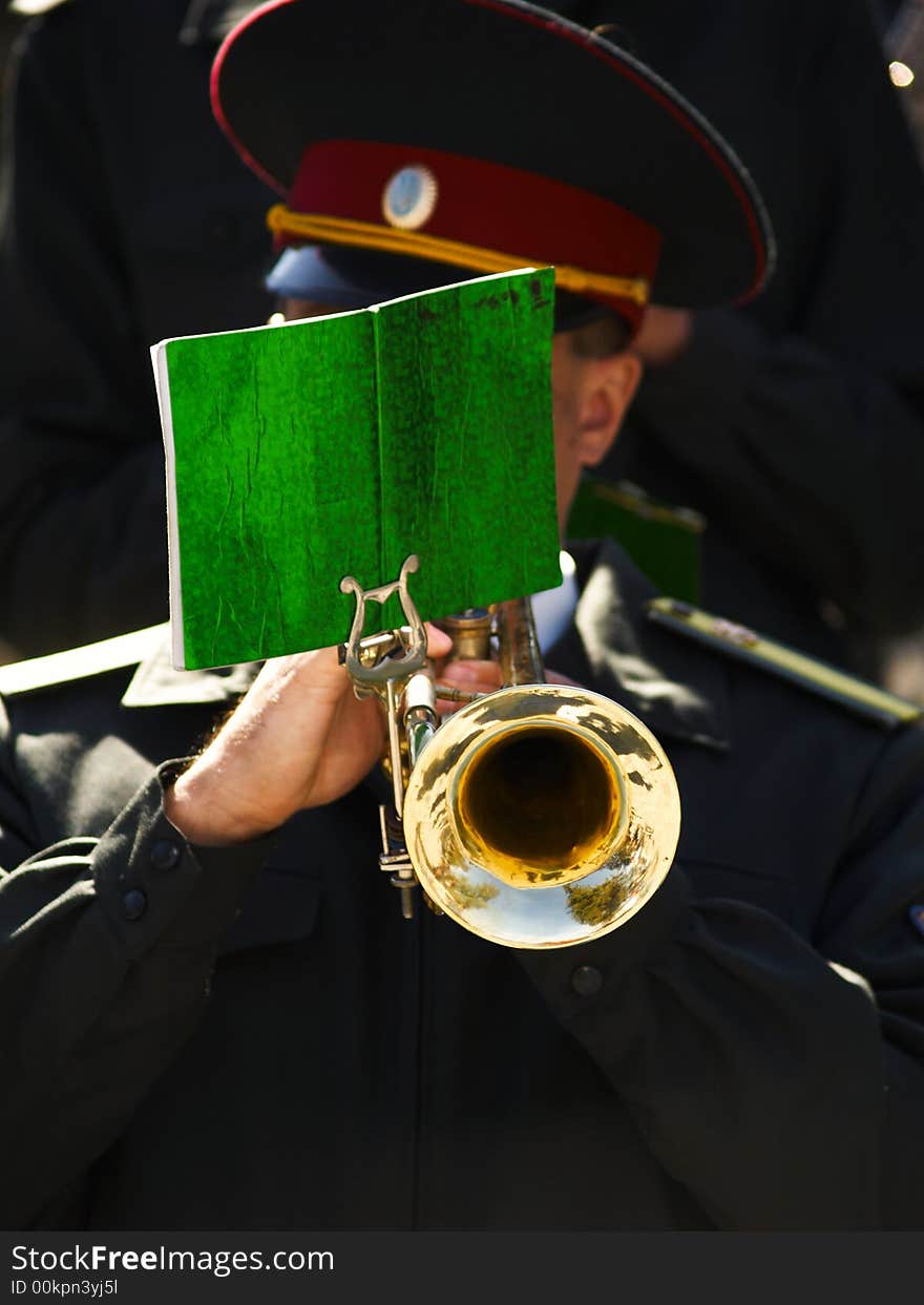 The man in uniform plays on a trumpet. The man in uniform plays on a trumpet