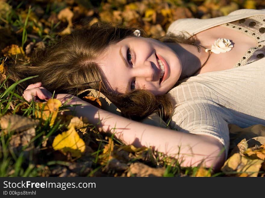 Laughing Girl lying in autumn leaves on sunset time. Laughing Girl lying in autumn leaves on sunset time