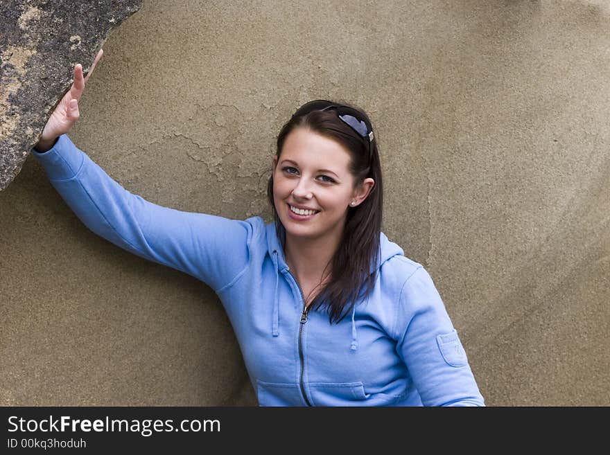 A pretty young woman by a sandstone rock is smiling. A pretty young woman by a sandstone rock is smiling.