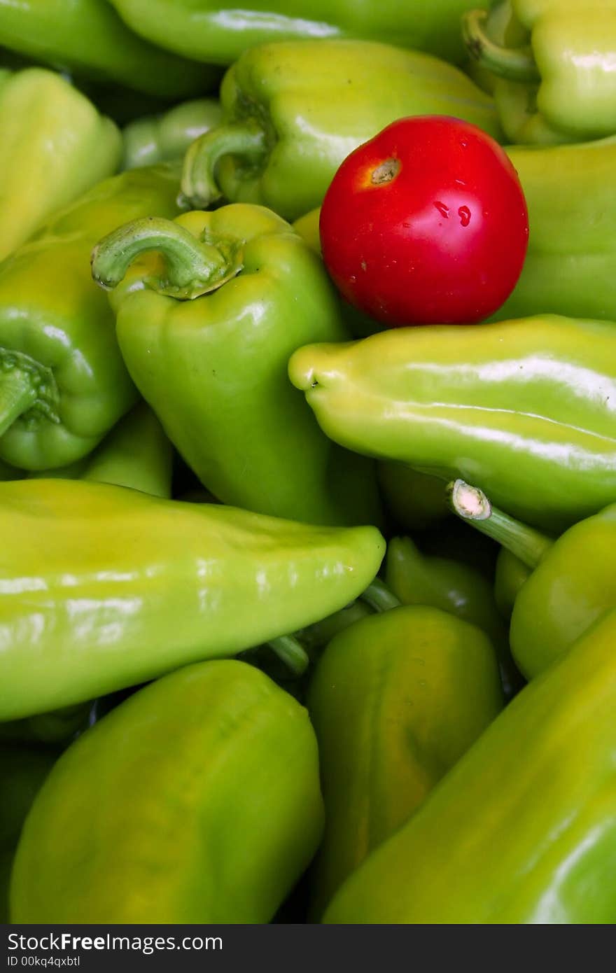 A red tomato on top of many green peppers, indicating uniqueness. A red tomato on top of many green peppers, indicating uniqueness.