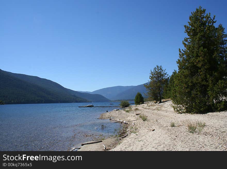 Blue water, sand, trees and mountains lanes in the back. Blue water, sand, trees and mountains lanes in the back