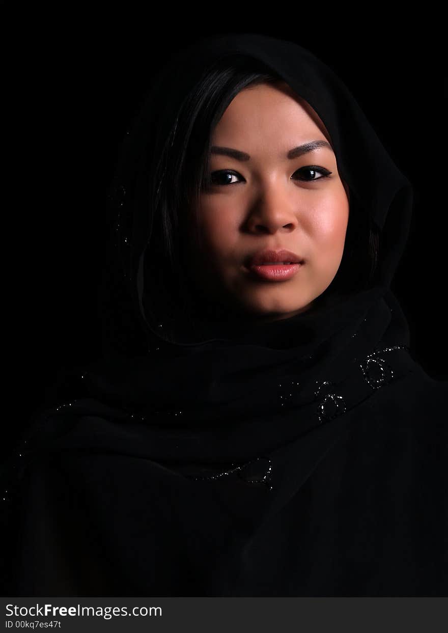 A Beautiful Asian shy looking girl over black with a balck scarf over her head. A Beautiful Asian shy looking girl over black with a balck scarf over her head