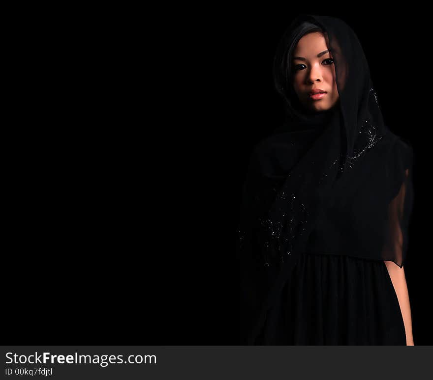 A Beautiful Asian shy looking girl over black with a black scarf over her head (lot's of copy space). A Beautiful Asian shy looking girl over black with a black scarf over her head (lot's of copy space)