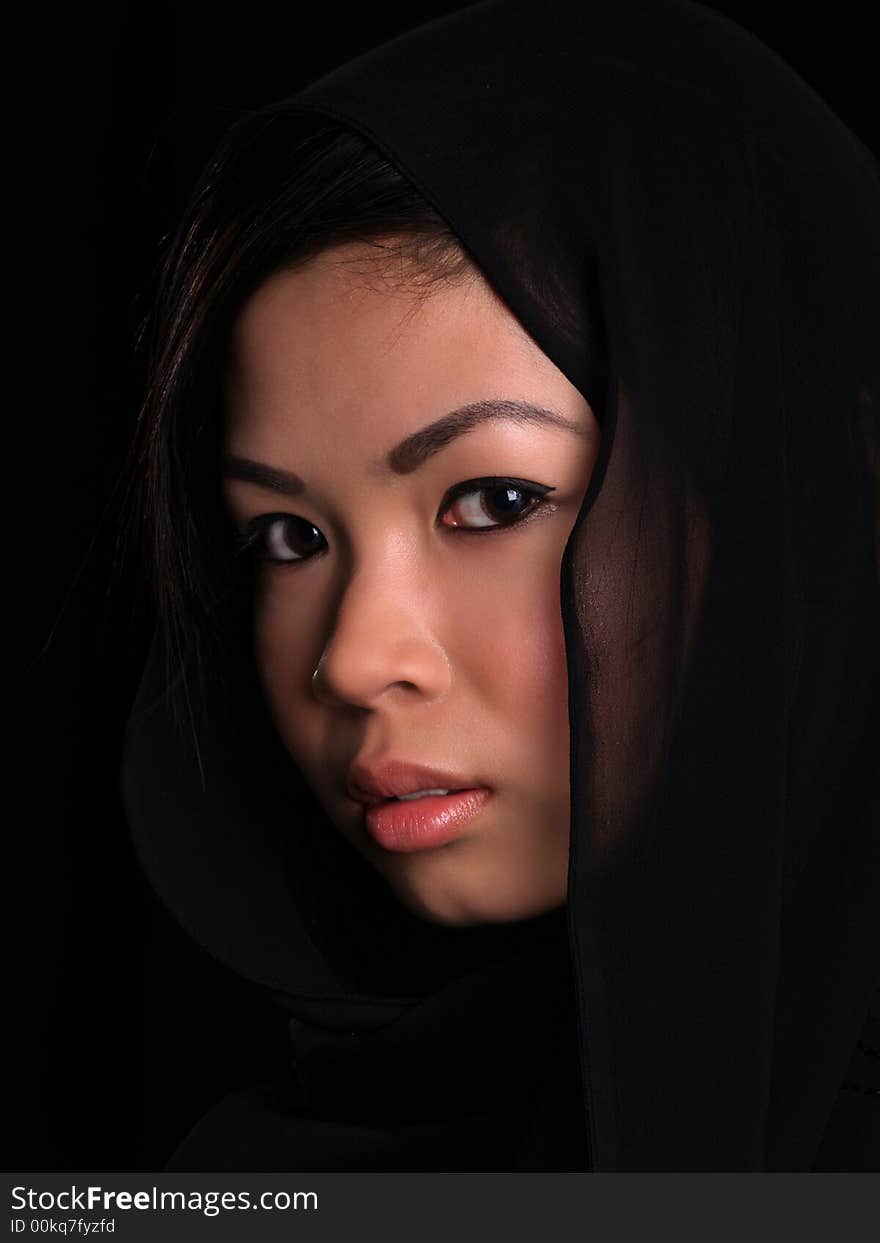 A Beautiful Asian shy looking girl over black with a black scarf over her head. A Beautiful Asian shy looking girl over black with a black scarf over her head