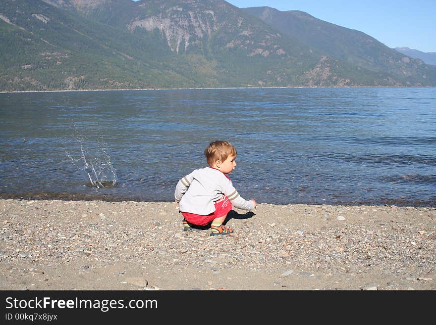 Small boy throwing stones in the water. Small boy throwing stones in the water